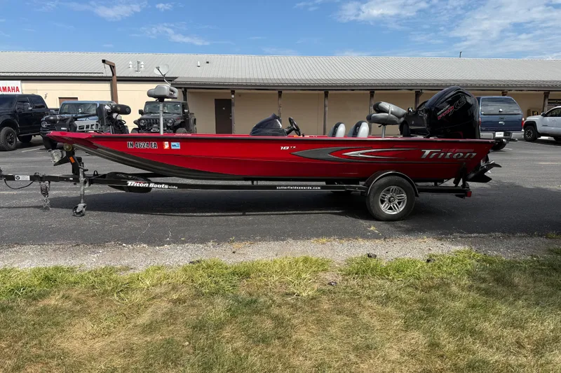 Slide: The Image of 2018 Triton 18 TX red fishing boat on trailer, parked outdoors. - 4