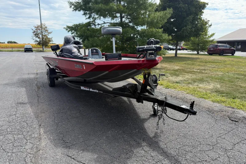 Slide: The Image of Red 2018 Triton 18 TX boat on trailer, parked on asphalt near trees. - 6