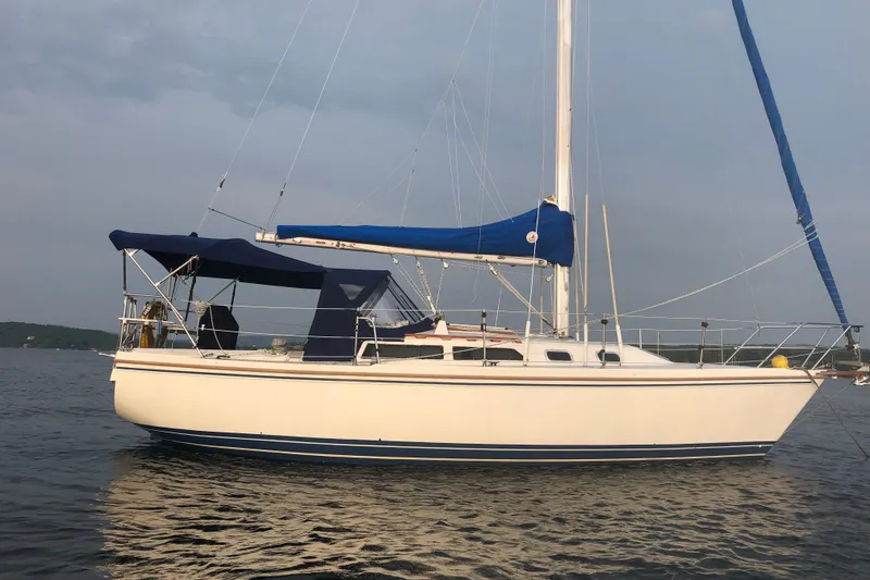 Slide: The Image of 1989 Catalina 30 MkII sailboat on calm water, featuring blue sails and canopy. - 1