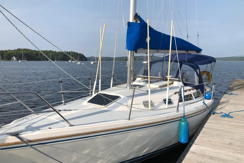 Slide: The Image of 1989 Catalina 30 MkII sailboat docked on a serene lake with blue canopy. - 2