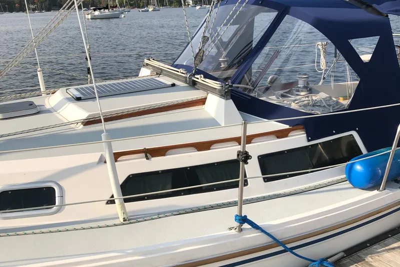 Slide: The Image of 1989 Catalina 30 MkII sailboat docked, featuring blue canopy and sleek design. - 3