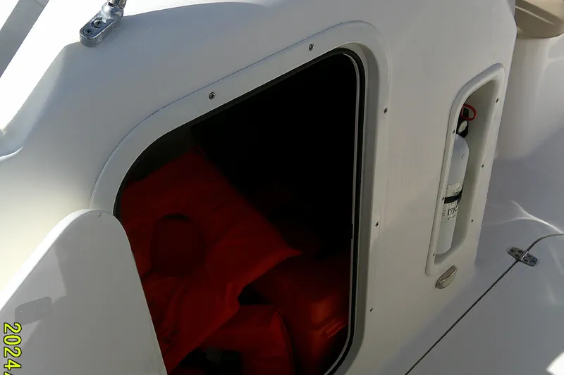 Slide: The Image of 2015 Pursuit DC 235 Dual Console boat storage compartment with life jackets and fire extinguisher. - 15
