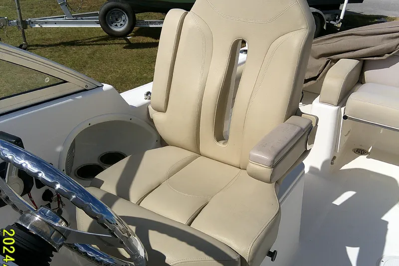 Slide: The Image of 2015 Pursuit DC 235 Dual Console boat with beige captain's seat and steering wheel. - 17