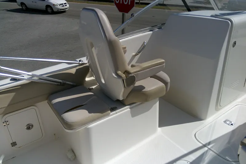 Slide: The Image of 2015 Pursuit DC 235 Dual Console boat interior with beige seating and storage compartments. - 23
