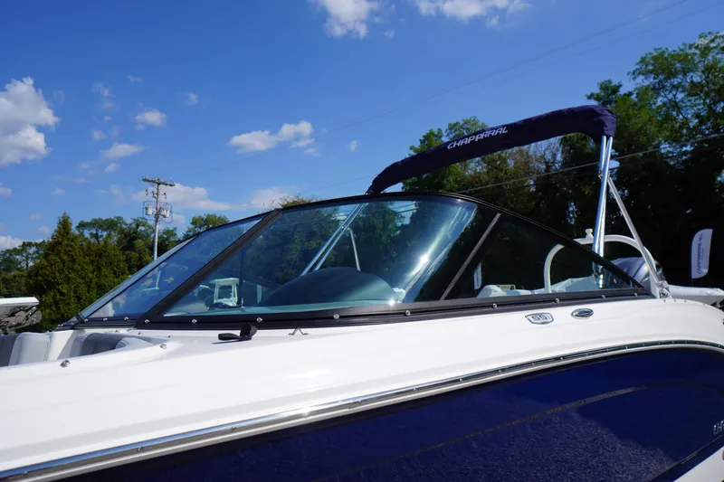 Slide: The Image of 2026 Chaparral 21 SSi OB boat with blue and white exterior under clear sky. - 2