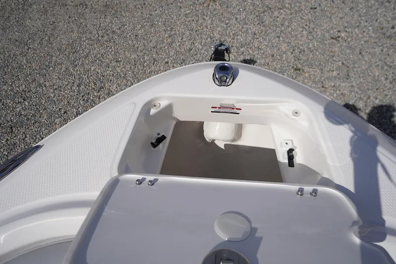 Slide: The Image of 2026 Chaparral 21 SSi OB boat storage compartment, open and empty, on gravel surface. - 5