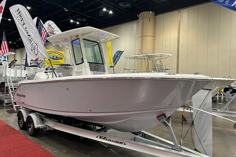 Slide: The Image of 2026 Sailfish 232 CC boat displayed indoors on a trailer with flags. - 4