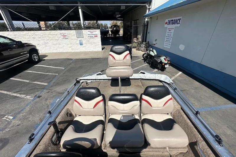 Slide: The Image of 2001 Bass Tracker Pro Team 175 boat with seating, parked near a building entrance. - 15