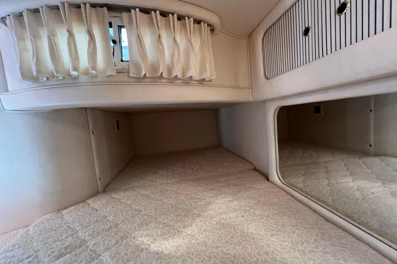 Slide: The Image of Interior cabin of 2001 Sea Ray 290 Sundancer with cozy bedding and window curtains. - 22