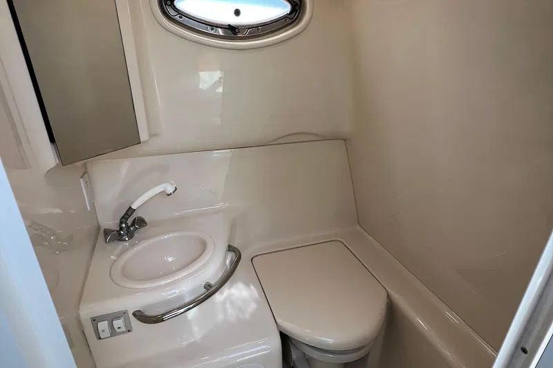 Slide: The Image of 2001 Sea Ray 290 Sundancer bathroom with sink, toilet, and porthole window. - 23