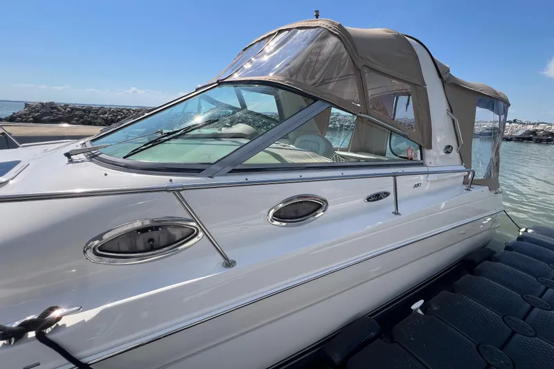 Slide: The Image of 2001 Sea Ray 290 Sundancer boat docked, featuring sleek design and beige canopy. - 5