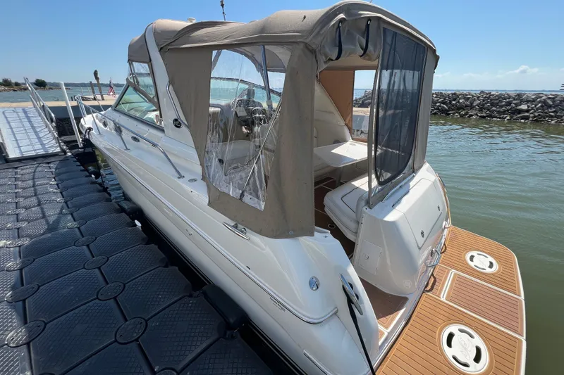 Slide: The Image of 2001 Sea Ray 290 Sundancer docked, featuring tan canopy and spacious deck. - 6