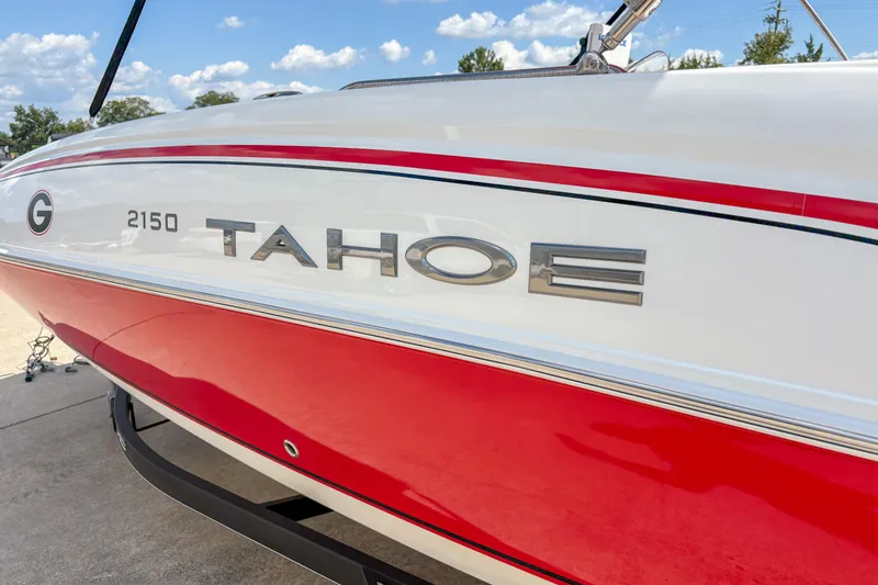 Slide: The Image of 2019 Tahoe 2150 boat with red and white exterior, parked outdoors under blue sky. - 2