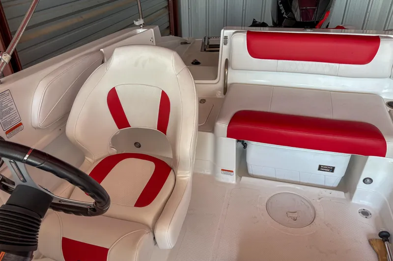 Slide: The Image of 2019 Tahoe 2150 boat interior with red and white seating, steering wheel, and storage compartment. - 20
