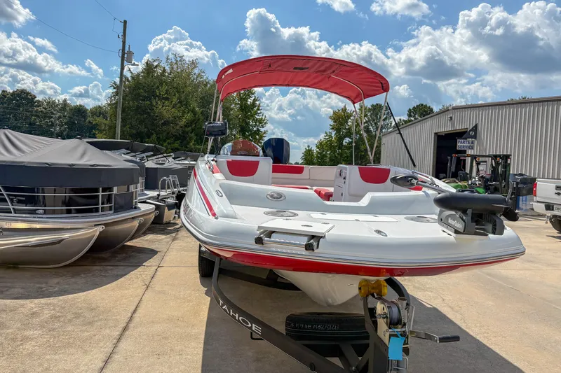 Slide: The Image of 2019 Tahoe 2150 boat with red canopy on trailer, parked outdoors under a cloudy sky. - 3