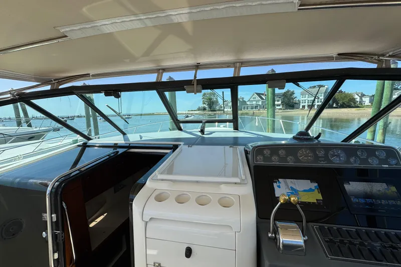 Slide: The Image of 2000 Tiara Yachts 3500 Express cockpit with navigation controls, docked by waterfront homes. - 15