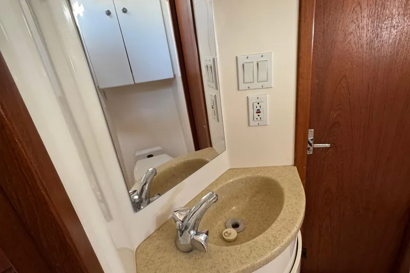 Slide: The Image of Bathroom sink area in 2000 Tiara Yachts 3500 Express, featuring mirror and wooden door. - 50