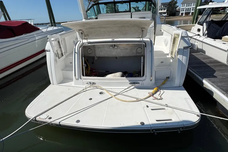 Slide: The Image of 2000 Tiara Yachts 3500 Express docked, rear view with open storage compartment. - 6