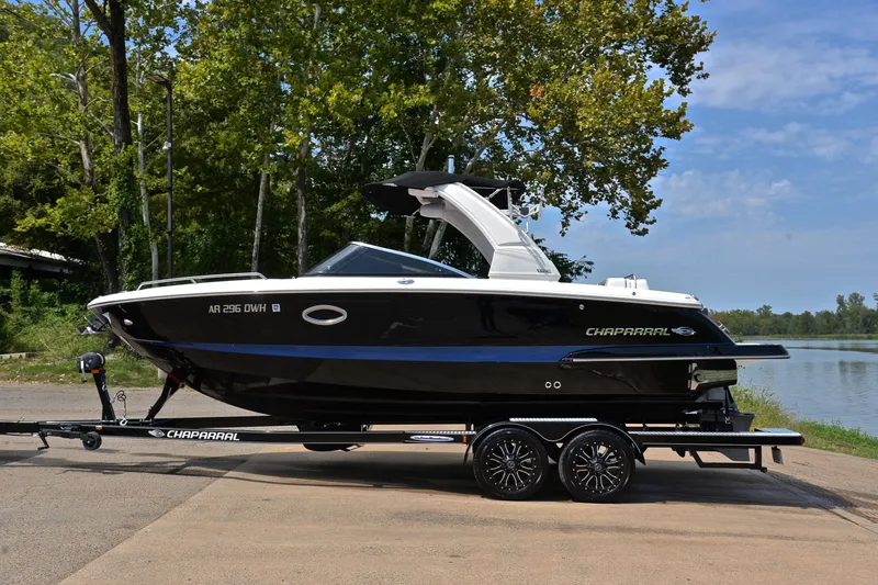 Slide: The Image of 2020 Chaparral 25 Surf boat on trailer by a lake, surrounded by trees. - 13