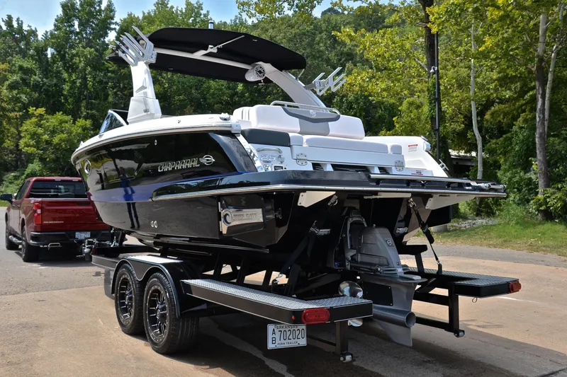Slide: The Image of 2020 Chaparral 25 Surf boat on trailer, parked outdoors near trees. - 14
