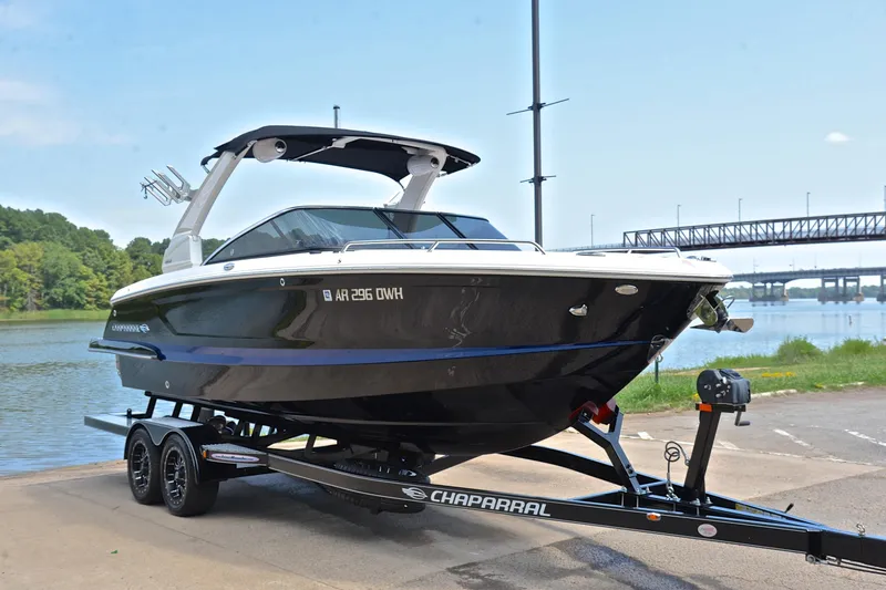 Slide: The Image of 2020 Chaparral 25 Surf boat on trailer by a river with bridge in background. - 18
