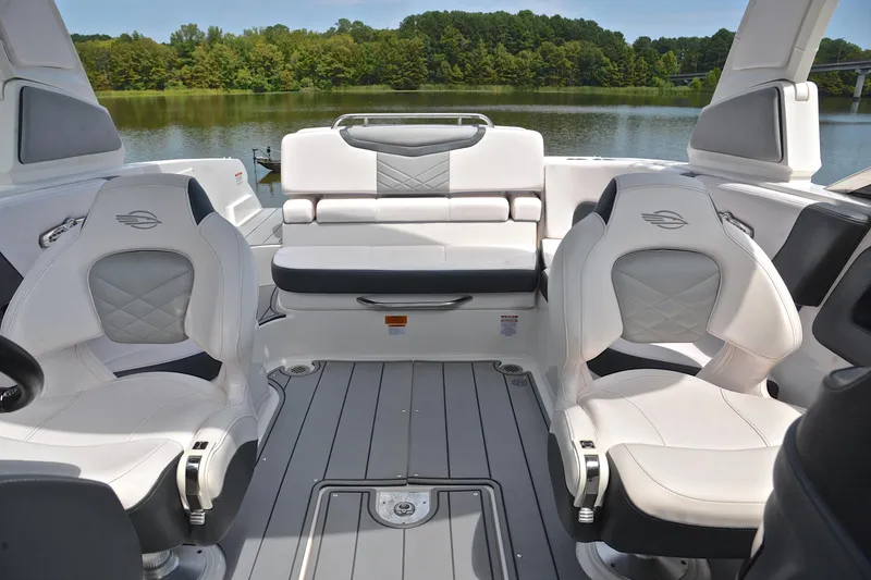 Slide: The Image of 2020 Chaparral 25 Surf boat interior with white seating, on a serene lake background. - 24