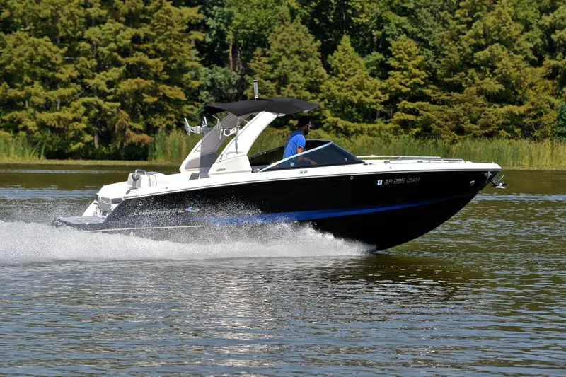 Slide: The Image of 2020 Chaparral 25 Surf boat cruising on a lake with lush green trees. - 3