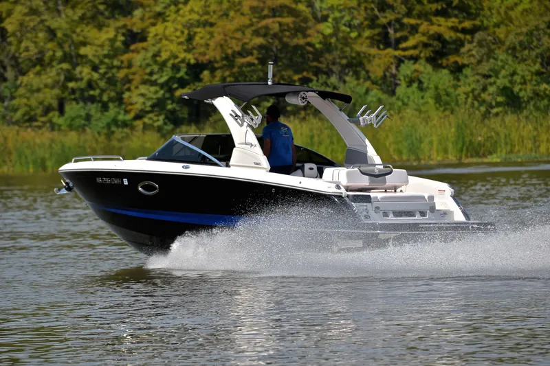 Slide: The Image of 2020 Chaparral 25 Surf boat cruising on a lake with lush green background. - 4