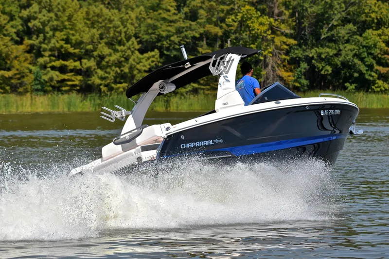 Slide: The Image of 2020 Chaparral 25 Surf boat cruising on a lake with lush green trees. - 5