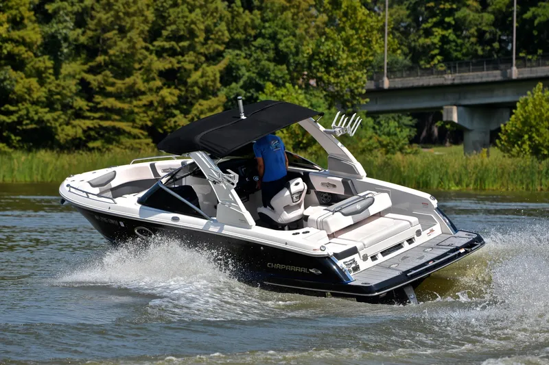 Slide: The Image of 2020 Chaparral 25 Surf boat cruising on a scenic river with lush greenery. - 7