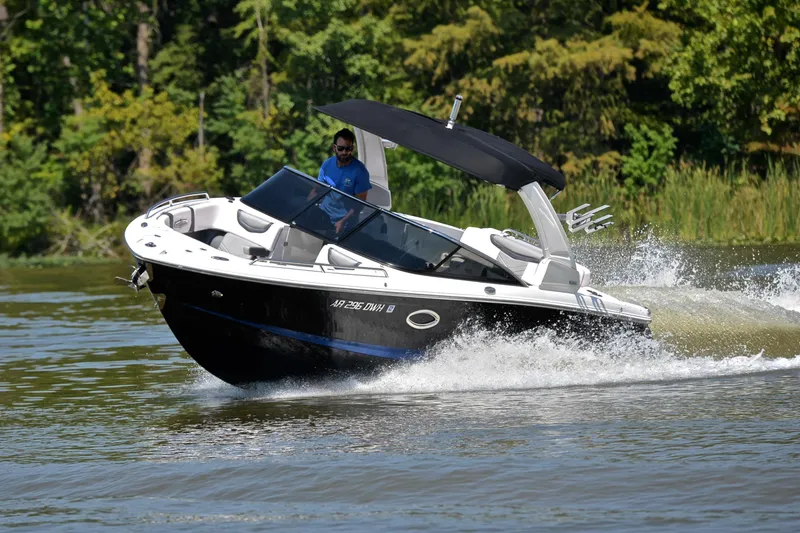 Slide: The Image of 2020 Chaparral 25 Surf boat cruising on a lake with lush green background. - 8