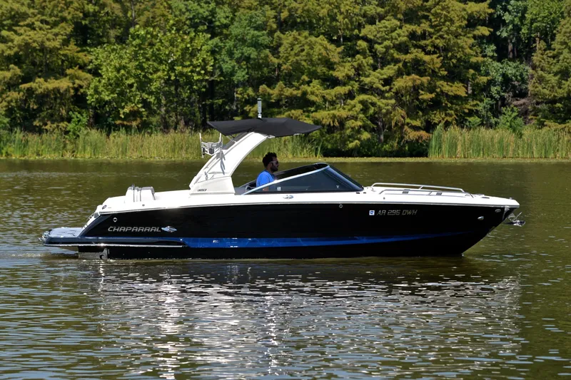 Slide: The Image of 2020 Chaparral 25 Surf boat cruising on a calm lake with lush green trees. - 9