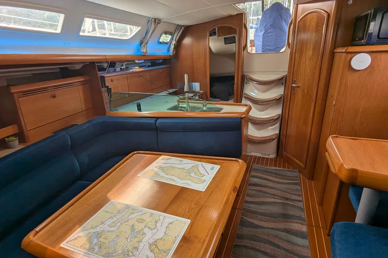 Slide: The Image of Interior of 2002 Jeanneau Sun Odyssey 37 sailboat with wooden furnishings and nautical maps. - 12