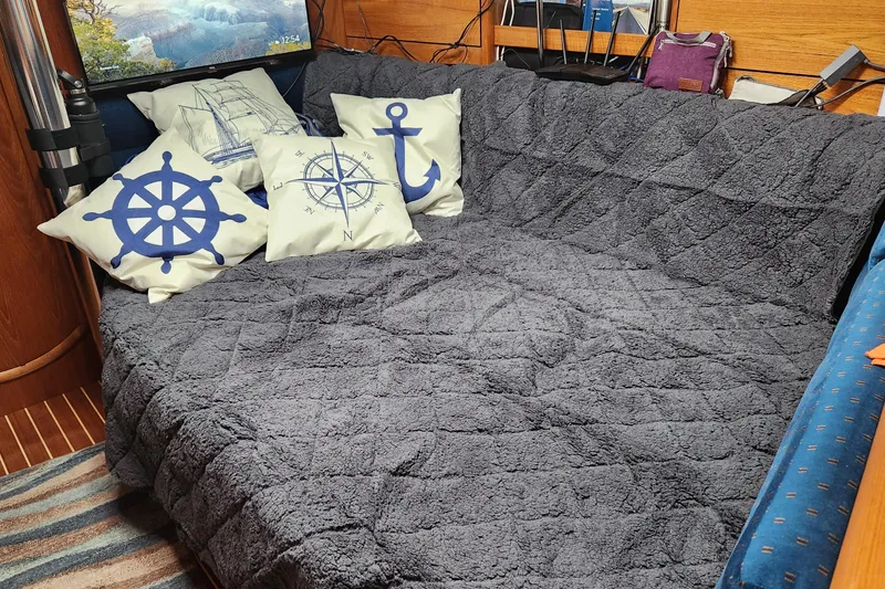 Slide: The Image of Cozy interior of 2002 Jeanneau Sun Odyssey 37 with nautical-themed pillows and plush blanket. - 13