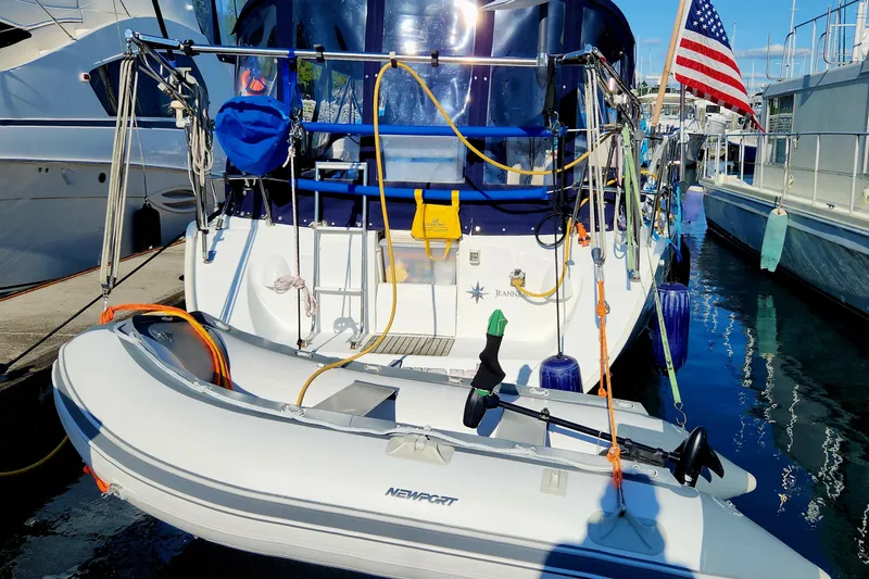 Slide: The Image of Jeanneau Sun Odyssey 37 sailboat, 2002 model, docked with dinghy and American flag. - 2