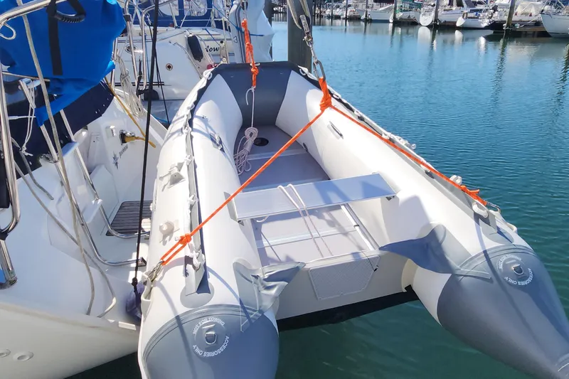 Slide: The Image of Inflatable dinghy attached to a 2002 Jeanneau Sun Odyssey 37 sailboat in a marina. - 4