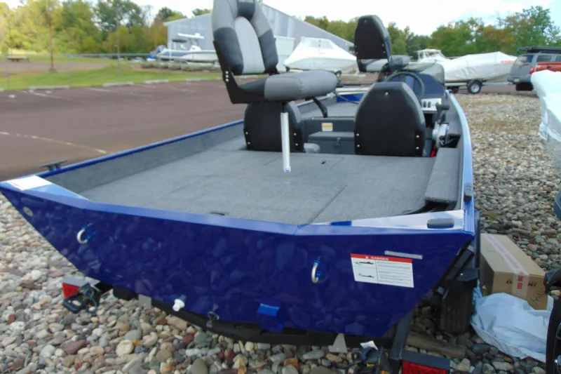 Slide: The Image of 2026 Crestliner 1700 Storm boat, blue exterior, spacious deck, comfortable seating, parked outdoors. - 4