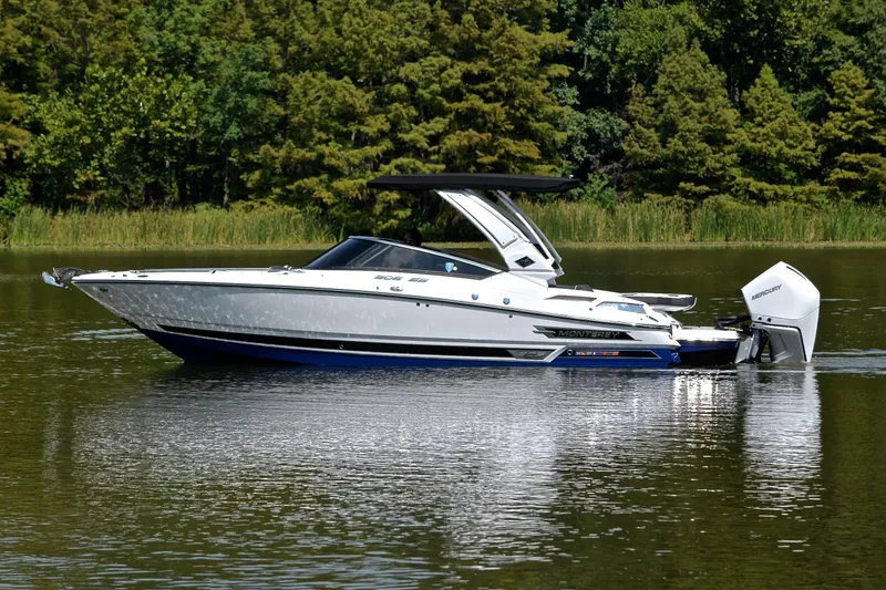 Slide: The Image of 2024 Monterey 305 Super Sport boat on a calm lake with lush green trees. - 11