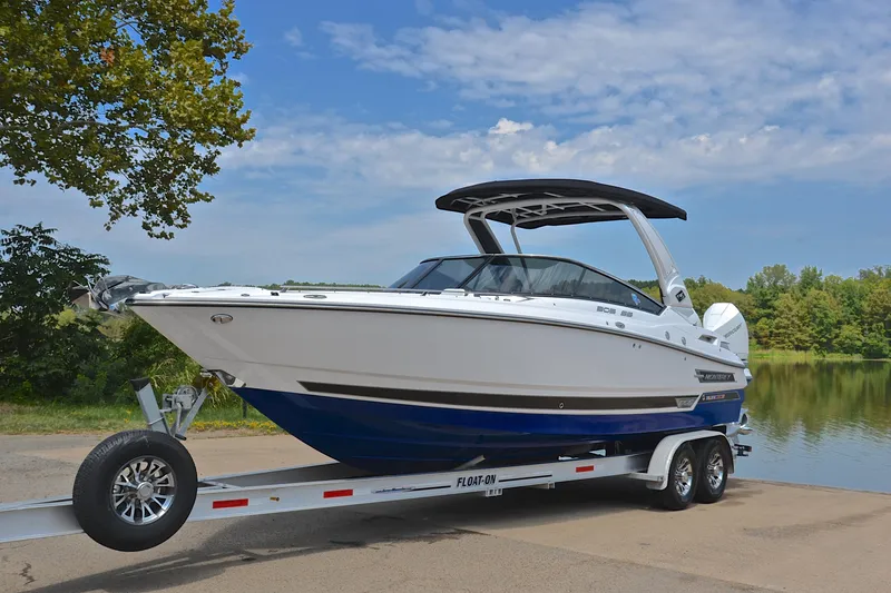Slide: The Image of 2024 Monterey 305 Super Sport boat on trailer by a lake under blue sky. - 12