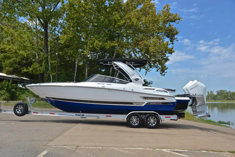 Slide: The Image of 2024 Monterey 305 Super Sport boat on trailer by a lake, surrounded by trees. - 13