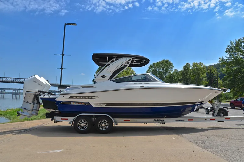 Slide: The Image of 2024 Monterey 305 Super Sport boat on trailer by riverside, under clear blue sky. - 17