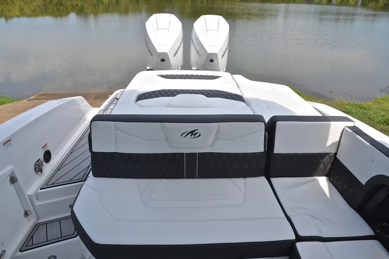 Slide: The Image of 2024 Monterey 305 Super Sport boat with luxurious seating and dual Mercury engines on a serene lake. - 25