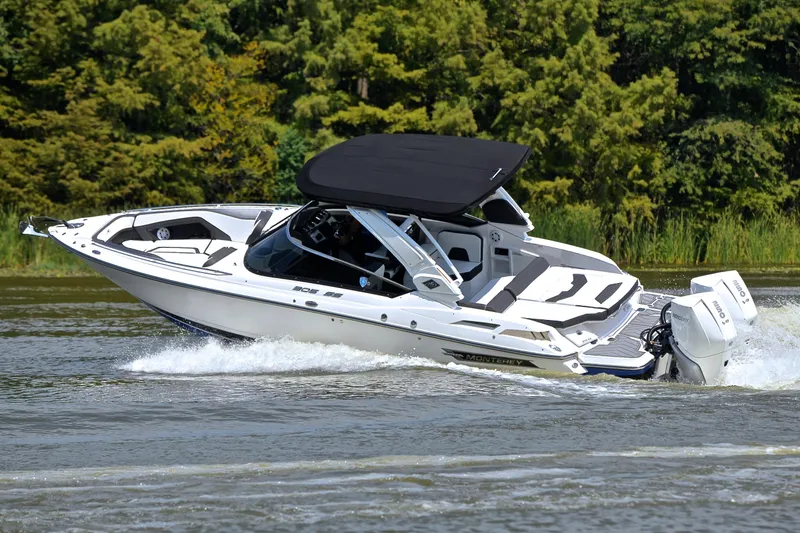 Slide: The Image of 2024 Monterey 305 Super Sport boat cruising on a lake with lush greenery. - 7