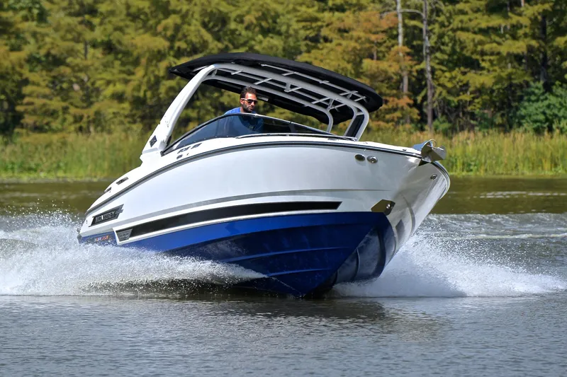 Slide: The Image of 2024 Monterey 305 Super Sport boat cruising on a lake with lush greenery. - 8