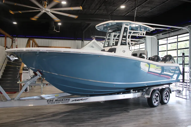 Slide: The Image of 2026 Tidewater 256 LXF boat in showroom, blue hull, on trailer. - 3
