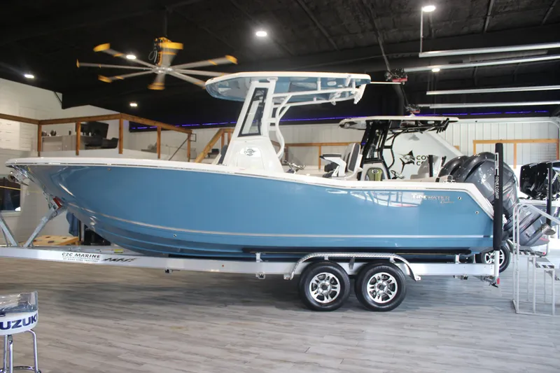 Slide: The Image of 2026 Tidewater 256 LXF boat in showroom, blue hull, on trailer, indoor display. - 4