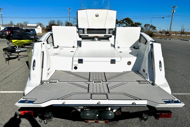 Slide: The Image of 2021 Scarab 195 ID boat rear view, showcasing spacious deck and seating in a parking lot. - 11