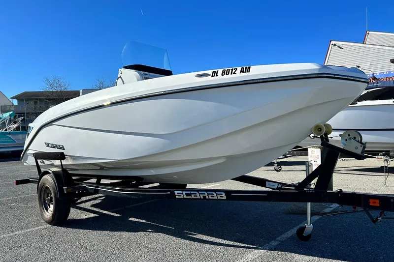 Slide: The Image of 2021 Scarab 195 ID boat on trailer under clear blue sky. - 2
