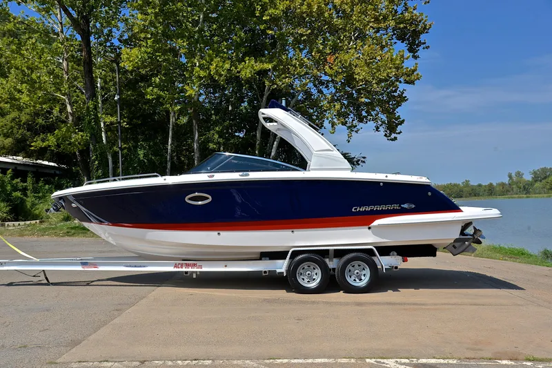 Slide: The Image of 2019 Chaparral 277 SSX boat on trailer by a lakeside, under clear blue sky. - 13