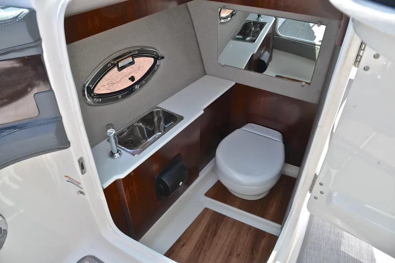 Slide: The Image of 2019 Chaparral 277 SSX boat interior with sink, toilet, and mirror in compact bathroom. - 29